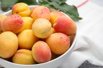 Many fresh apricots in bowl on table, closeup