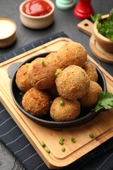 Delicious fried croquette balls with parsley and green onion on grey textured table, closeup