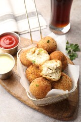 Delicious fried croquette balls and sauces on grey textured table, closeup