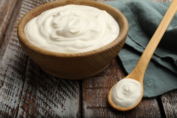 Tasty sour cream on wooden table, closeup