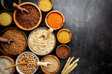 Organic products. Bowls with different gluten free grains on black background, top view