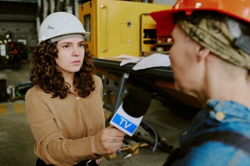 Caucasian young adult woman holding microphone interviewing middle aged Caucasian woman wearing...
