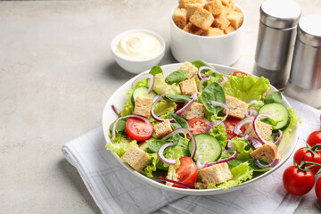 Delicious salad with croutons and vegetables served on light grey table, closeup. Space for text