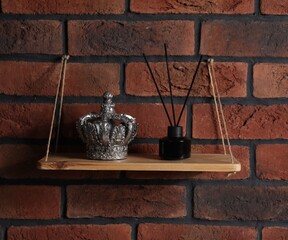 Wooden shelf with reed diffuser and home decor on brick wall