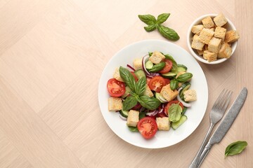 Delicious salad with croutons, vegetables and basil on wooden table, flat lay. Space for text