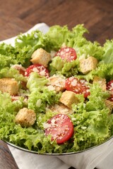 Tasty salad with croutons, tomatoes, cheese and chicken on wooden table, closeup