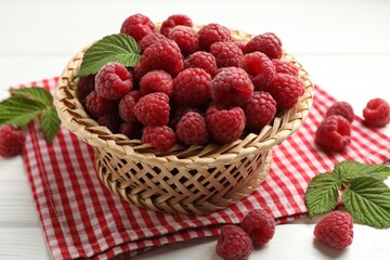 Tasty fresh ripe raspberries and leaves on white wooden table, closeup