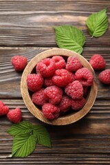 Tasty fresh ripe raspberries and leaves on wooden table, flat lay