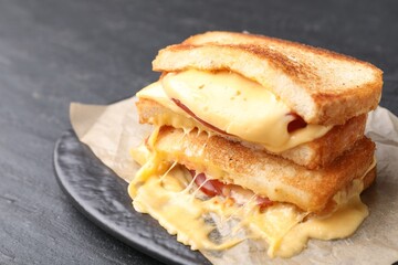 Tasty sandwiches with melted cheese and ham on black table, closeup
