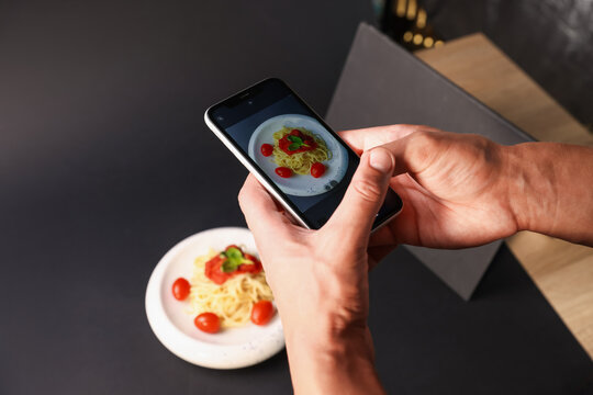 Man taking picture of pasta with smartphone in studio, closeup. Professional food photography - Powered by Adobe
