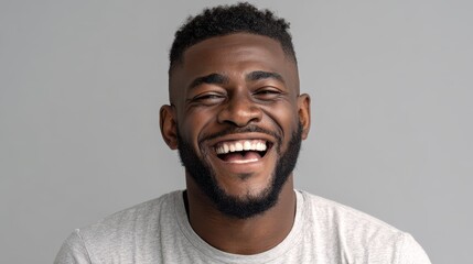 handsome unshaven young darkskinned male laughing out loud at funny meme he found on internet smiling broadly showing his white straight teeth positive human facial expressions and emotions no logos 