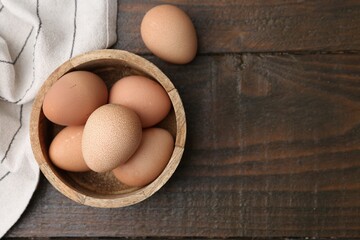 Raw chicken eggs in bowl on wooden table, top view. Space for text