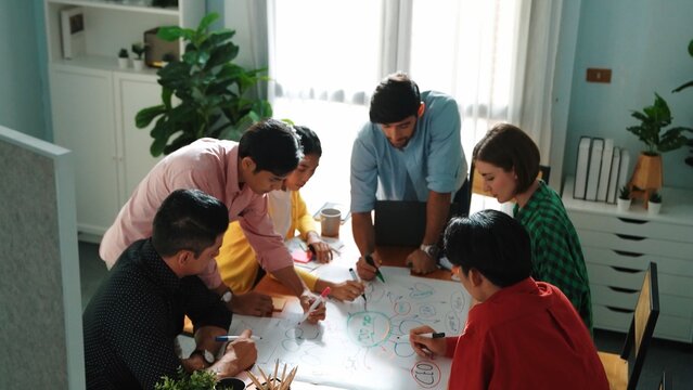 Top view of happy creative team putting hands together while drawing mind map. Group of diverse people working together brainstorming marketing idea and sharing plan by using sticky notes. Convocation