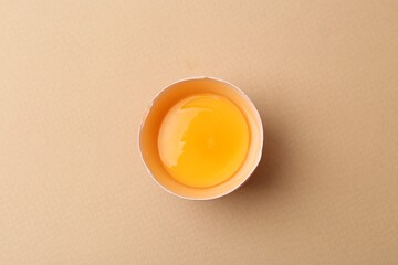 One broken chicken egg on beige background, top view
