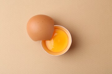 One broken chicken egg on beige background, top view