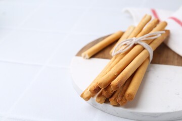 Delicious grissini sticks on white table, closeup. Space for text