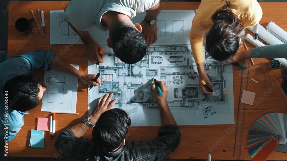 Poster top down view of civil engineer team writing at blueprint at meeting table with color palettes. grou