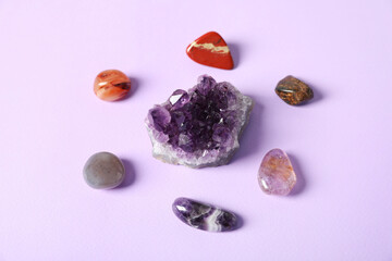 Aura. Different natural mineral stones on violet background, above view