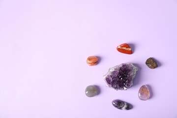 Aura. Different natural mineral stones on violet background, flat lay. Space for text