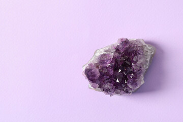 Aura. One beautiful amethyst on violet background, top view. Space for text