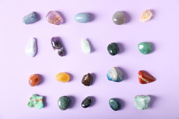 Aura. Different natural mineral stones on violet background, flat lay