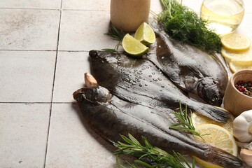 Seafood. Fresh raw flounder fish and spices on light tiled table, closeup. Space for text