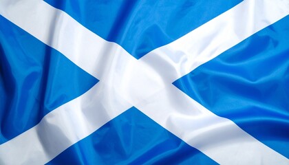 Scottish Saltire flag with white diagonal cross on blue, flying against sky and distant mountains&mdash;symbol of heritage and national pride.
