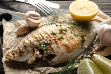 Tasty roasted flounder fish with spices served on wooden table, closeup. Homemade seafood dish