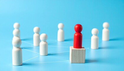 A red figure on a wooden block, surrounded by white figures, with a blue background, symbolizing leadership and teamwork. 