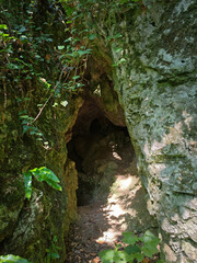 The forest-surrounded limestone entrance of Kő-lyuk II Cave in the Bükk Mountains, Hungary,...