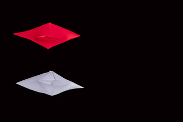 Paper boats Leadership and standing out from the crowd in white and red with a black background.