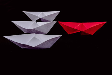 Paper boats Leadership and standing out from the crowd in white and red with a black background.
