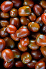 A vibrant pattern photograph featuring small, ripe cherry tomatoes. Their rich red color and smooth, glossy skins create a fresh, appetizing look, perfect for themes of healthy eating.