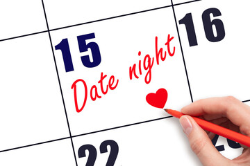 15th day of the month.  Hand writing Date night reminder and drawing a red heart on calendar with...