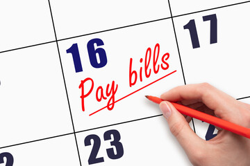 16th day of the month.  Hand writing Pay bills reminder and drawing a line on calendar with red pen...
