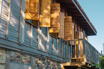 Wooden shutters adorn a rustic house in a serene countryside setting during the golden hour of late...