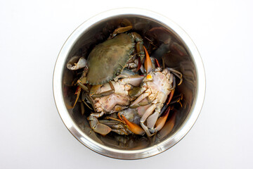 Several fresh raw crabs in a large stainless steel bowl, ready to be cooked.