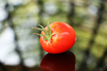 Fresh tomatoes on a black mirror background.