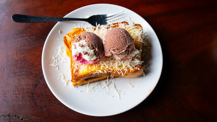 toast, ice cream and cheese flakes on a white plate on the table