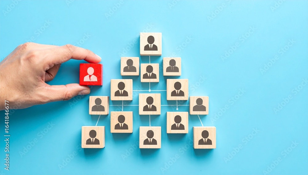 Poster a hand places a red cube into a pyramid structure made of wooden blocks, symbolizing teamwork and hi