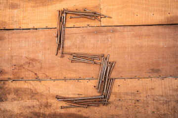 Rusty nails on wood. Close-up of worn planks and variously shaped metal fasteners.