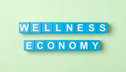 Fototapeta premium Wellness economy concept spelled out with blue blocks on a light green surface