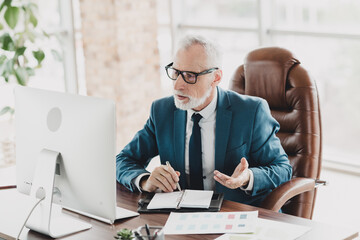 Mature businessman in a corporate setting discussing strategies at a desk with documents and a...