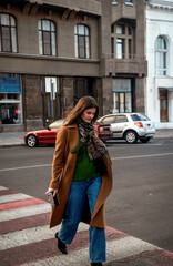 Fototapeta premium Attractive woman walking down the street in a coat, in autumn