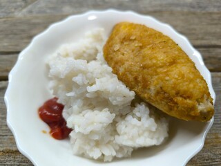 Kyiv cutlet with white rice on a plate on a wooden table