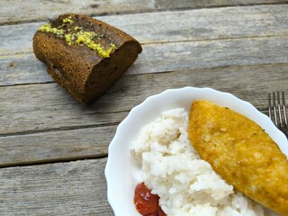 Kyiv cutlet with white rice on a plate on a wooden table