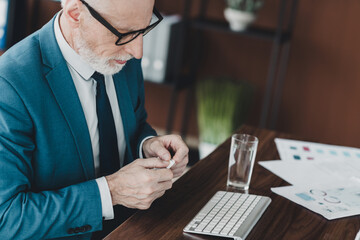 Confident mature businessman working in a modern office workspace and analyzing documents with...