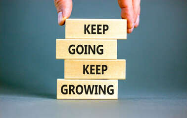 Keep going and growing symbol. Concept words phrase Keep going keep growing on beautiful wooden blocks. Beautiful grey background. Businessman's hand. Business Keep going growing concept. Copy space.