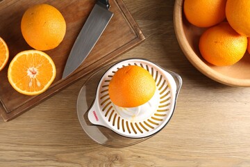 Making juice. Juicer, fresh oranges and knife on wooden table, flat lay