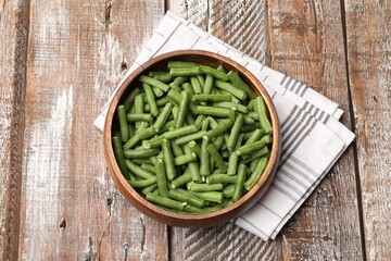 Pieces of fresh pea pods in bowl on color wooden table, top view